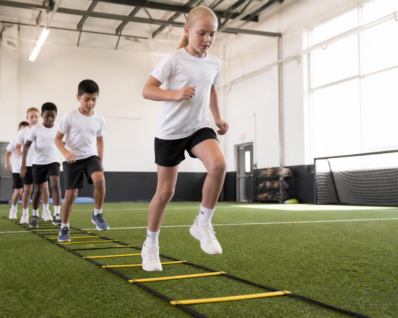 Young athletes moving through agility ladder drills on indoor turf